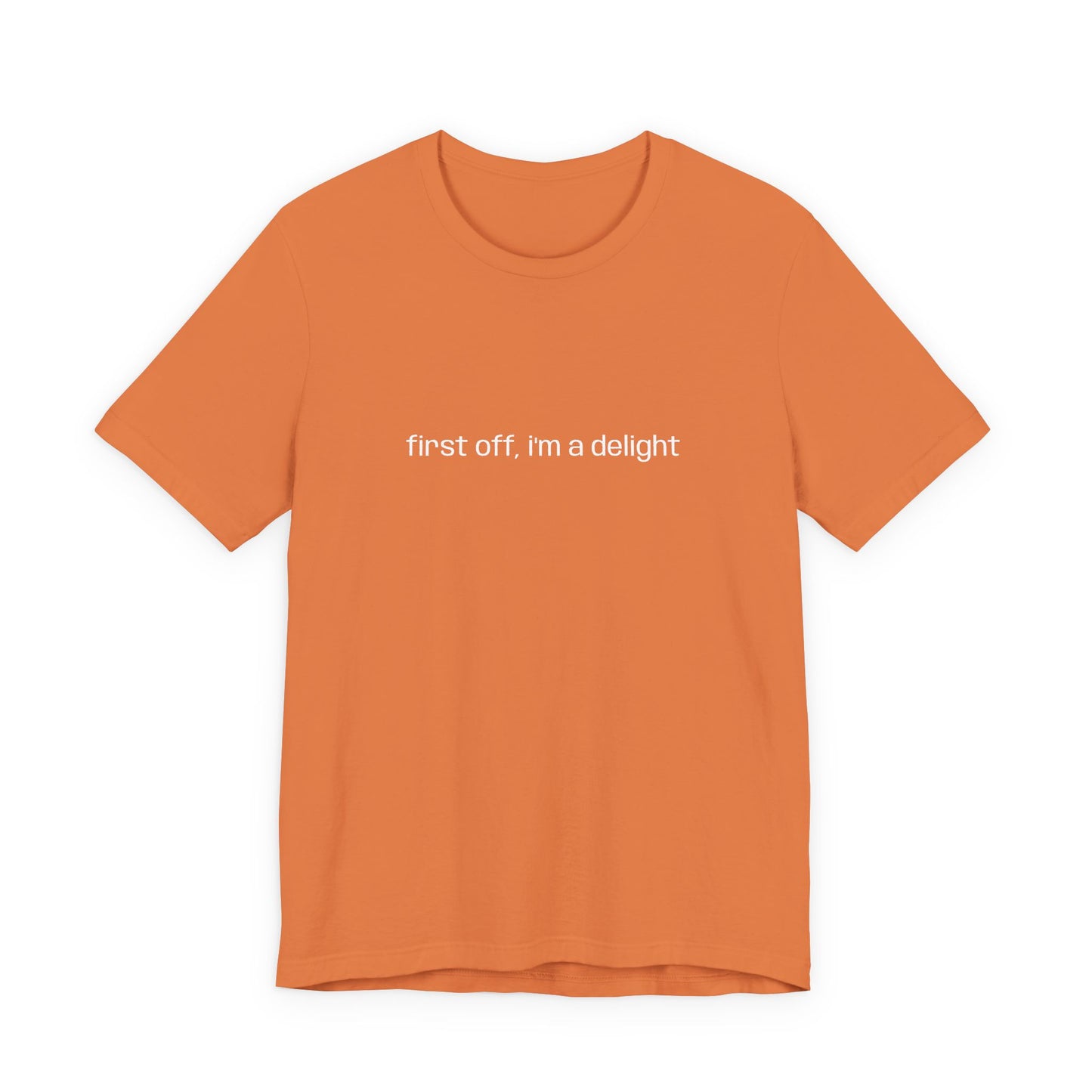 Close-up of folded orange t-shirt showcasing "first off, i'm a delight" printed in white