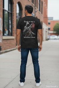 DailyThreadCo. black 100% cotton t-shirt with a graphic of a hooded reaper holding a bloody anatomical heart and the text 