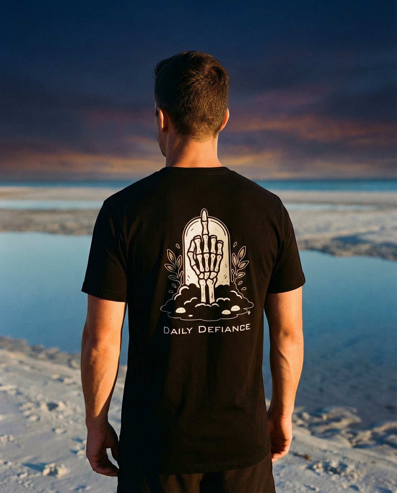 DailyThreadCo. black 100% cotton t-shirt with a graphic of a skeleton hand rising from earth with "Daily Defiance" text.