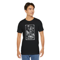DailyThreadCo. black 100% cotton t-shirt with 'The Fool' tarot card graphic print on the front. Features a skeleton figure, dog, and mountain landscape.