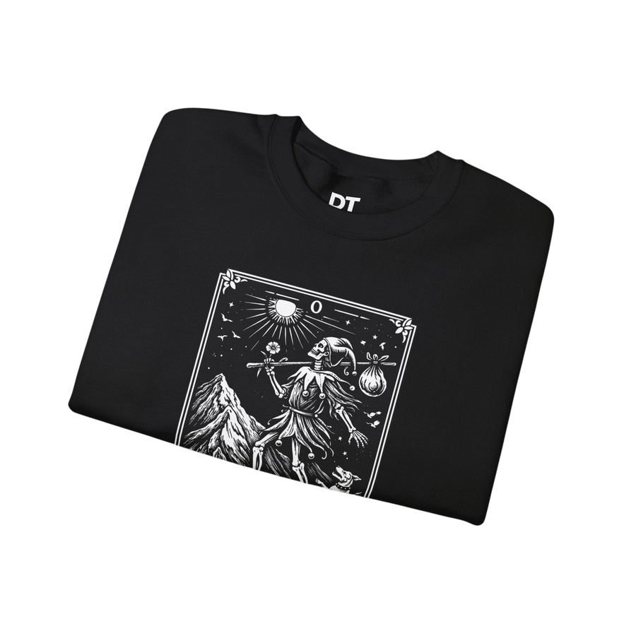 DailyThreadCo. black crewneck sweatshirt with a vintage tarot card graphic of "The Fool" featuring a skeleton figure, mountains, and celestial symbols.