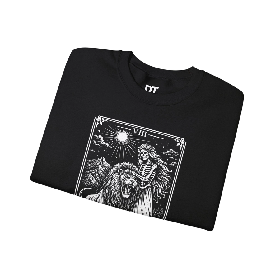 DailyThreadCo. black crewneck sweatshirt with a monochrome tarot strength card graphic featuring a skeleton figure, a lion, and mountains under a sun.