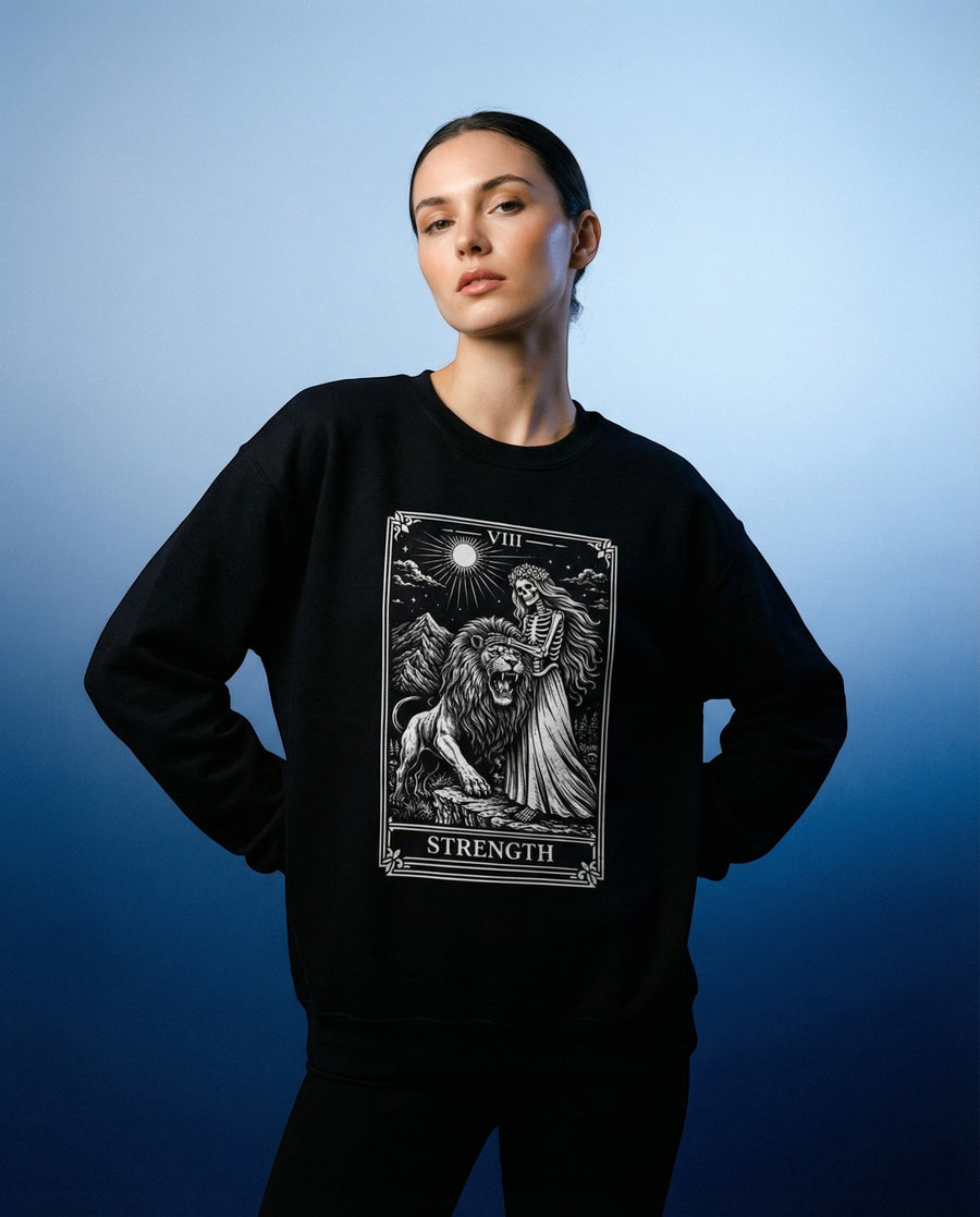 DailyThreadCo. black crewneck sweatshirt with a monochrome tarot strength card graphic featuring a woman and a lion.