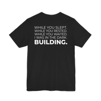 DailyThreadCo. black cotton t-shirt with white text that reads 'WHILE YOU SLEPT. WHILE YOU RESTED. WHILE YOU WAITED. I WAS IN THE DARK. BUILDING.'