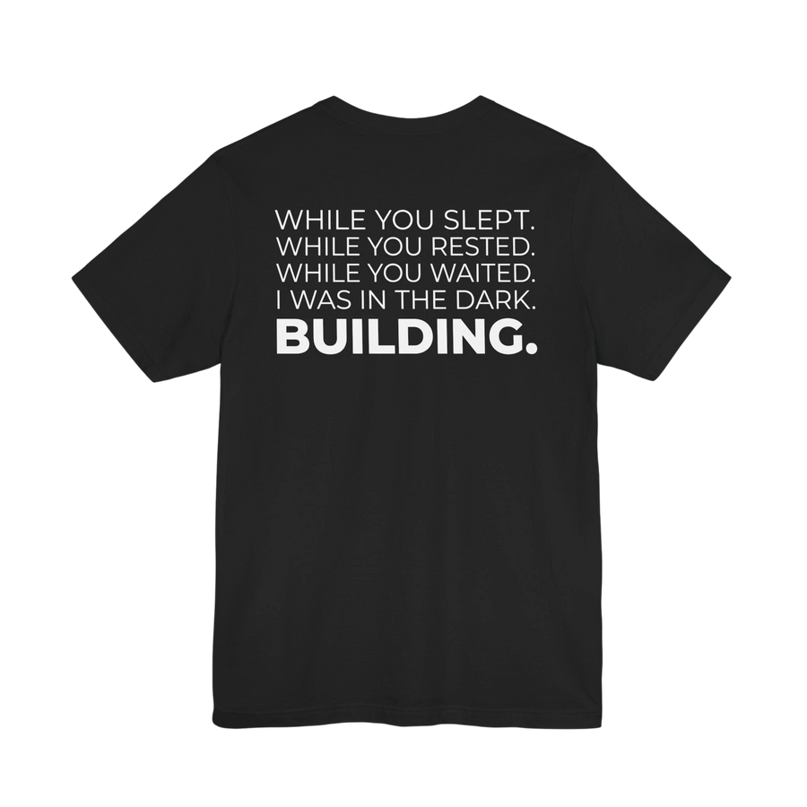DailyThreadCo. black cotton t-shirt with white text that reads 'WHILE YOU SLEPT. WHILE YOU RESTED. WHILE YOU WAITED. I WAS IN THE DARK. BUILDING.'