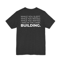 DailyThreadCo. dark grey cotton t-shirt with white text on back: 'While You Slept. While You Rested. While You Waited. I Was In The Dark. BUILDING.'