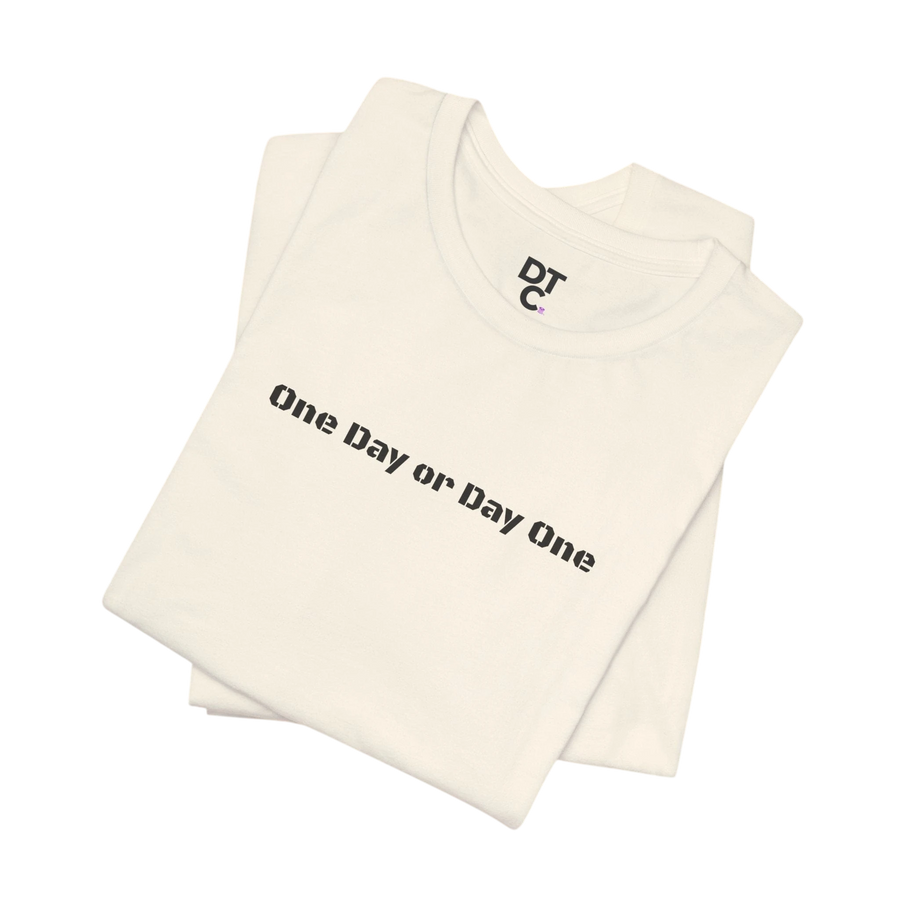 DailyThreadCo. cream cotton t-shirt with black "One Day or Day One" graphic print and DTC logo.