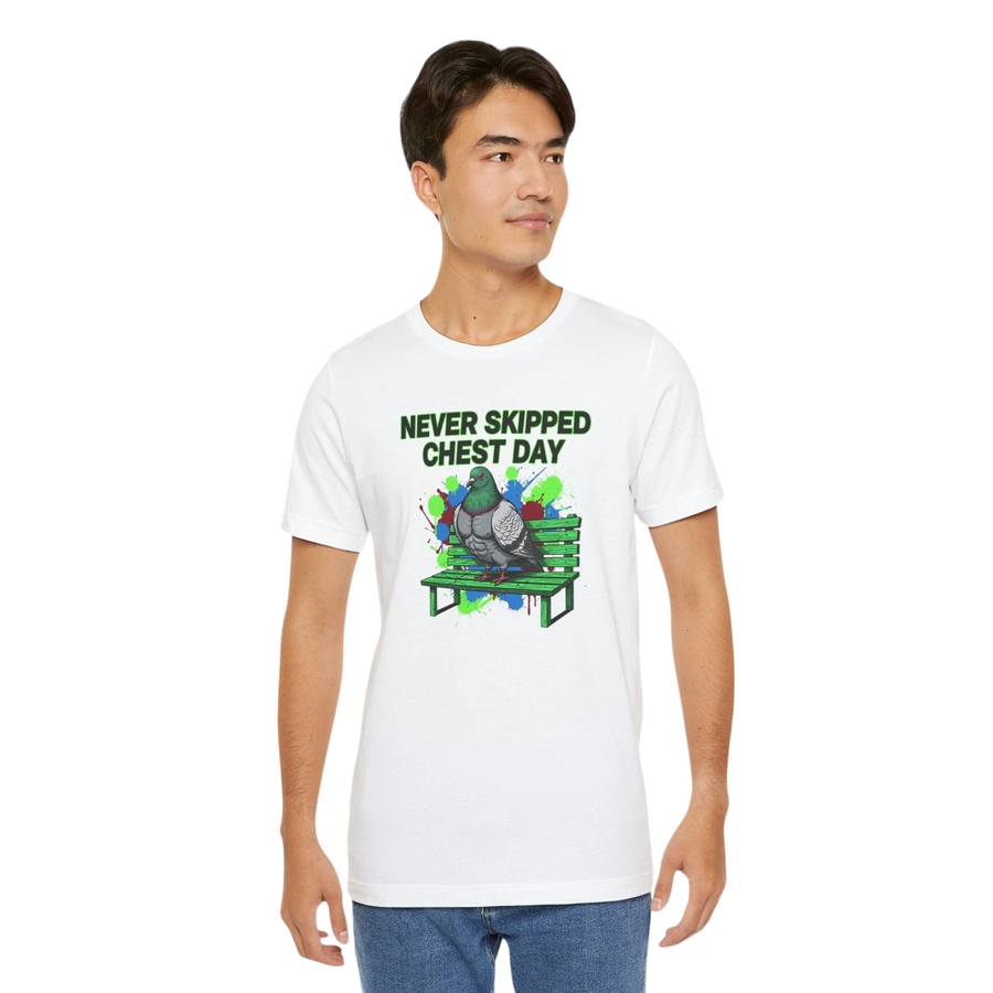 DailyThreadCo. white cotton t-shirt with a graphic of a muscular pigeon sitting on a park bench with colorful paint splatters and the text "NEVER SKIPPED CHEST DAY".