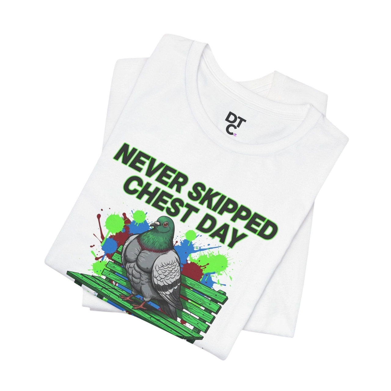 DailyThreadCo. white cotton t-shirt with a graphic print of a muscular pigeon on a green park bench, with colorful paint splatters and text "NEVER SKIPPED CHEST DAY".