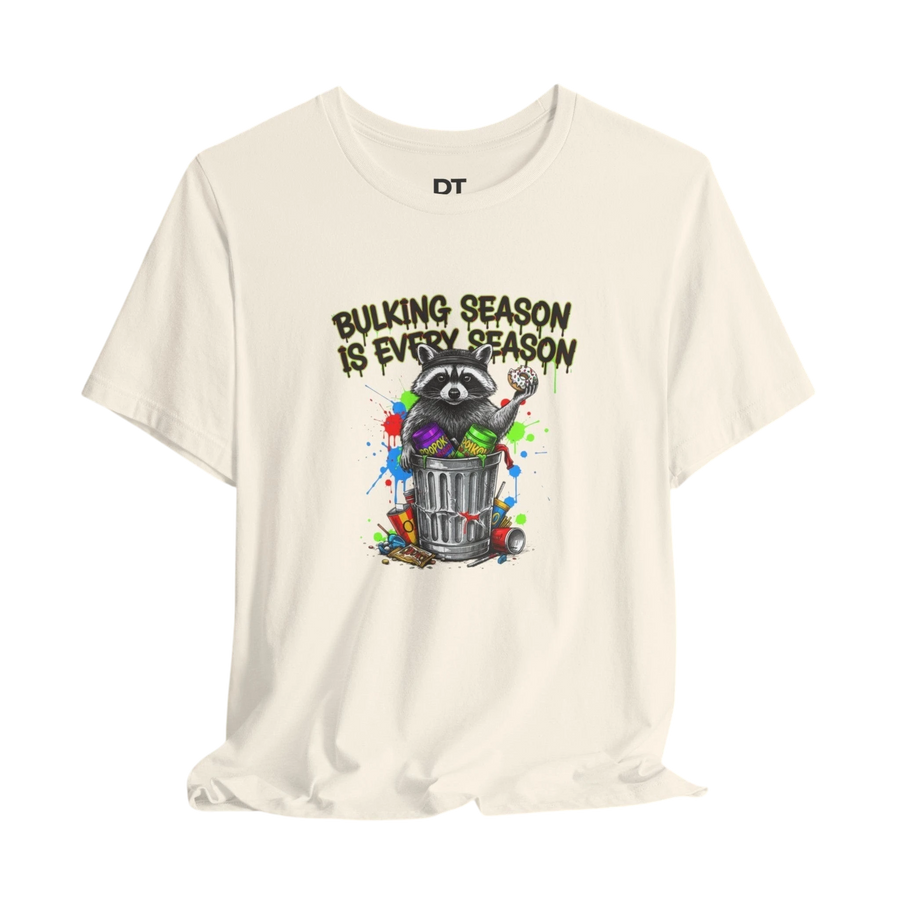 DailyThreadCo. cream 100% cotton t-shirt with a funny graphic of a raccoon in a trash can with the text "BULKING SEASON IS EVERY SEASON".