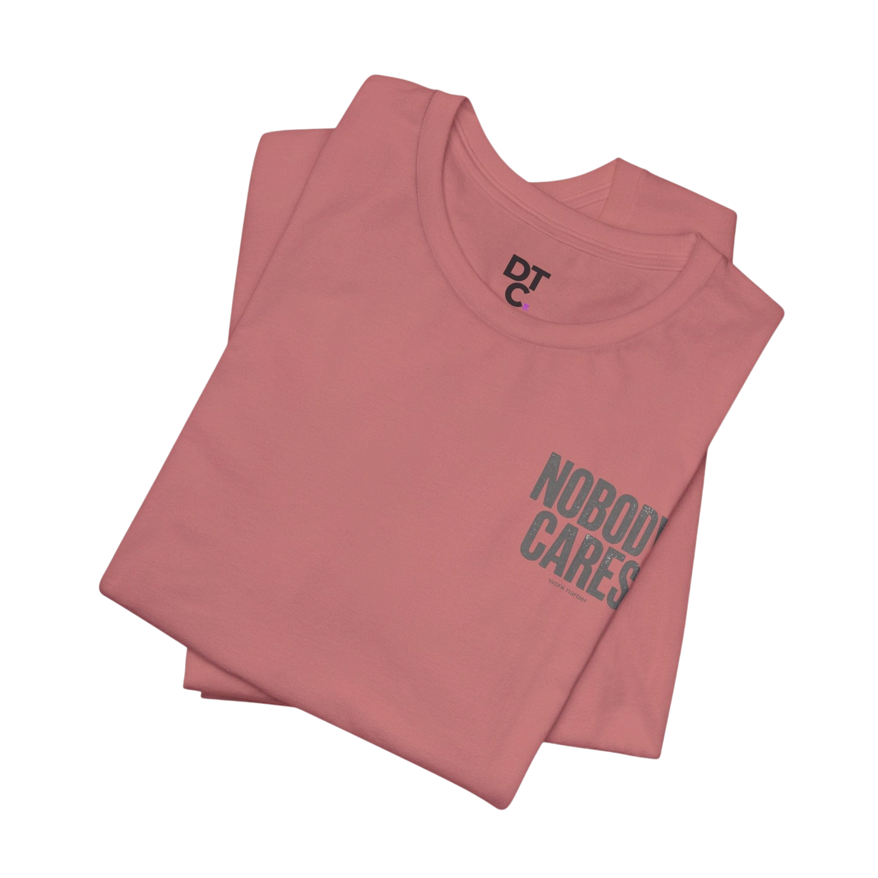 DailyThreadCo. pink cotton graphic tee with "Nobody Cares" text on the front and DTC logo on the neck.