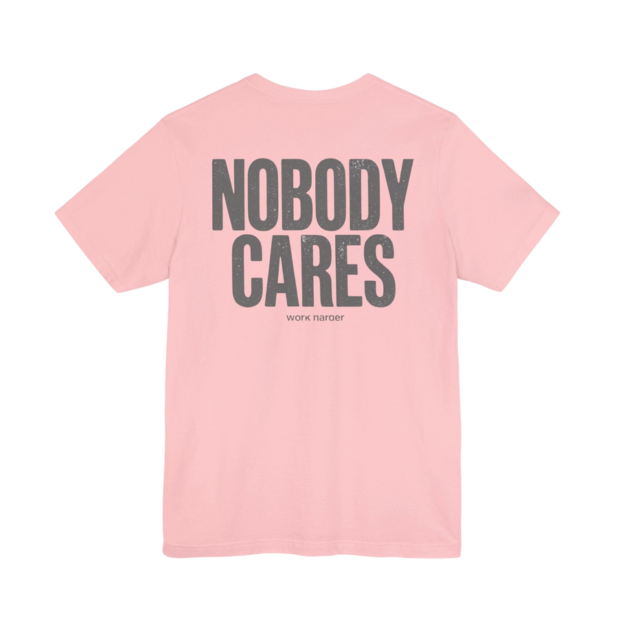 DailyThreadCo. pink 100% cotton graphic tee with "NOBODY CARES" and "work harder" text art in grey.