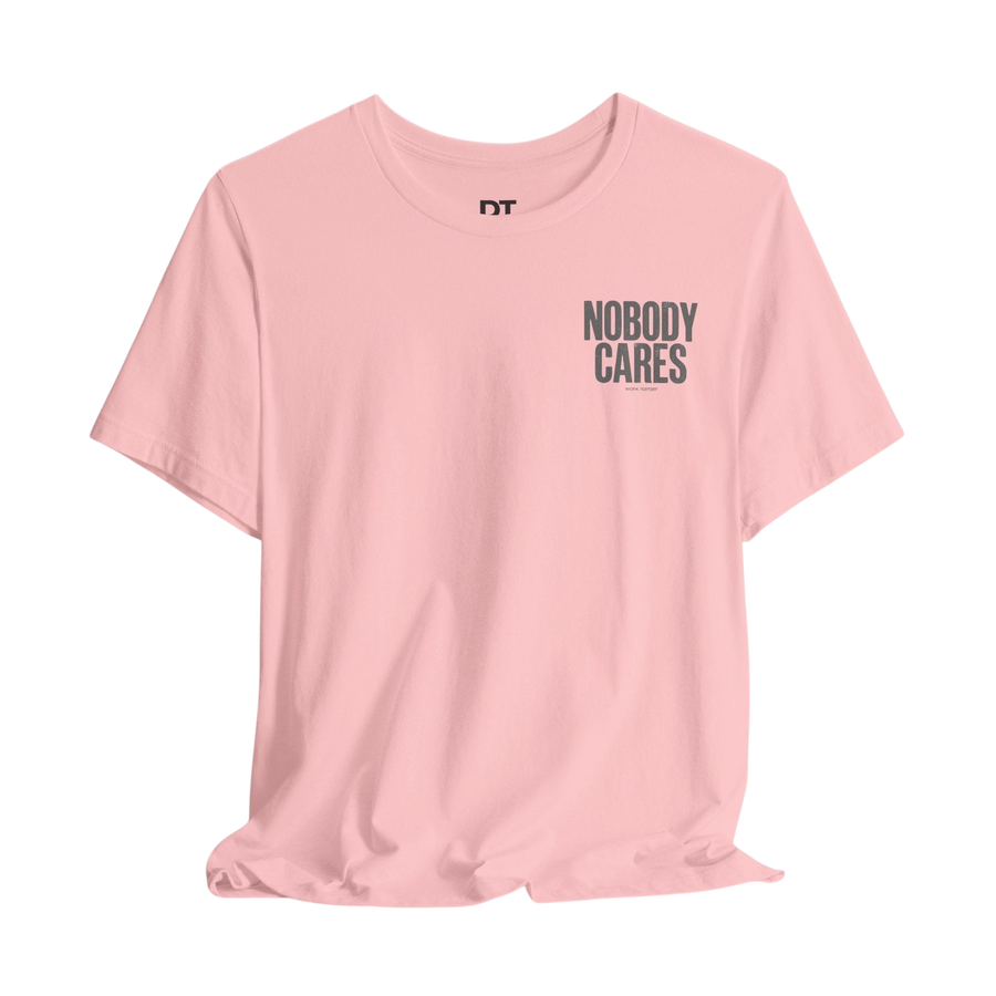 DailyThreadCo. light pink 100% cotton graphic tee with "Nobody Cares" text graphic on the chest.