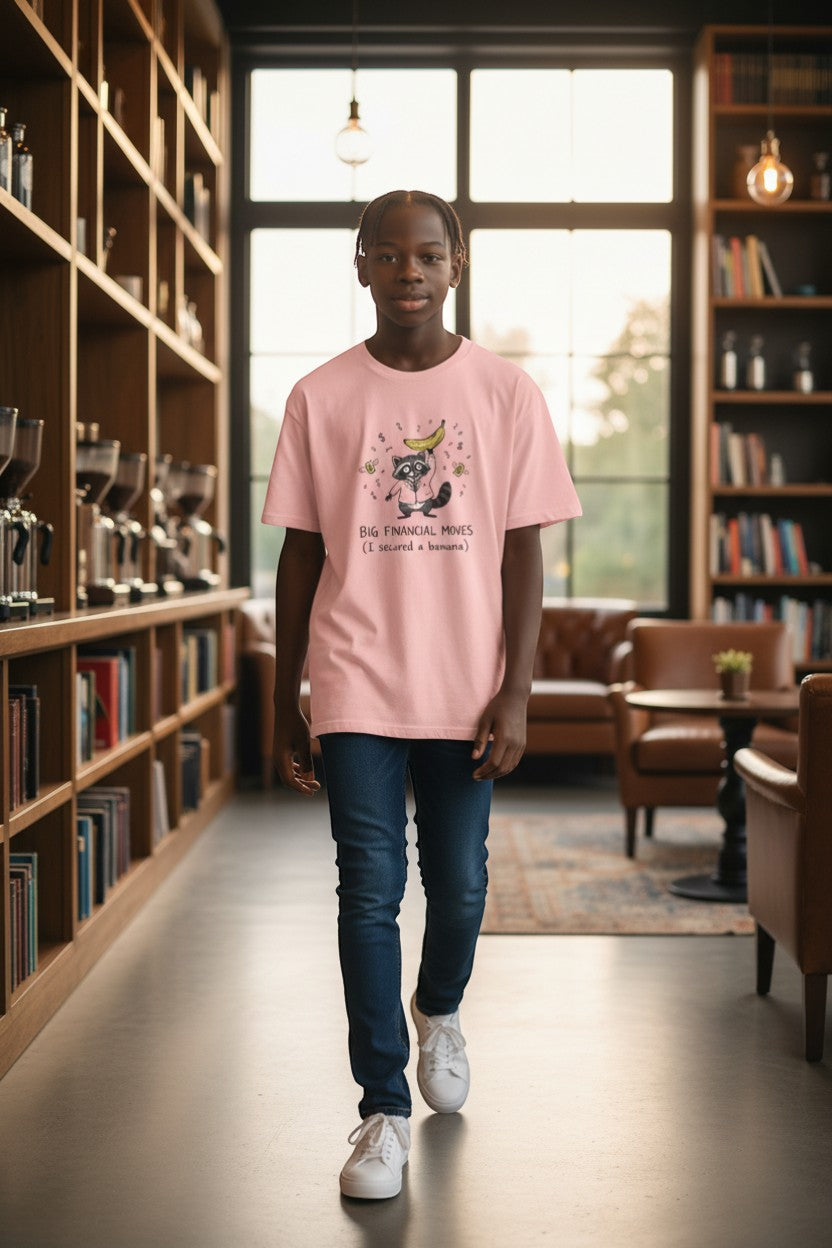 DailyThreadCo. light pink cotton t-shirt with a graphic of a raccoon holding a banana and the text "BIG FINANCIAL MOVES (I secured a banana)".