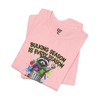 DailyThreadCo. pink 100% cotton t-shirt with a graphic of a raccoon in a trash can holding a donut and the text 