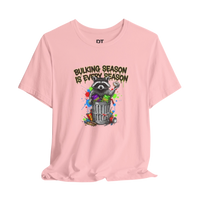 DailyThreadCo. pink 100% cotton t-shirt with a graphic of a raccoon in a trash can, holding a donut, with the text 