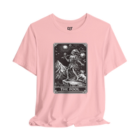 DailyThreadCo. pink cotton t-shirt with 'The Fool' tarot card graphic in black and white. Features a skeleton figure with a dog and mountain landscape.