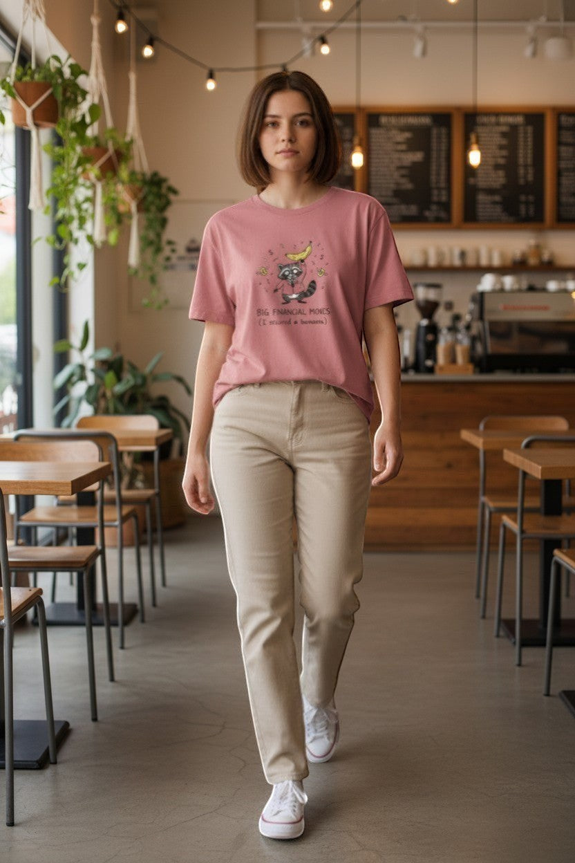 DailyThreadCo. dusty rose 100% cotton t-shirt with a graphic of a raccoon in a suit holding a banana, surrounded by money symbols.