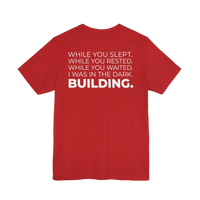 DailyThreadCo. red cotton t-shirt with white text on back: 'While You Slept. While You Rested. While You Waited. I Was In The Dark. BUILDING.'