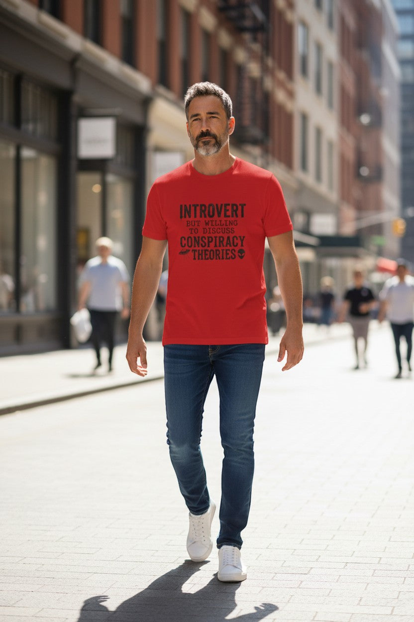 DailyThreadCo. red cotton t-shirt with black text that reads "INTROVERT BUT WILLING TO DISCUSS CONSPIRACY THEORIES" and graphics of a UFO and an alien head.