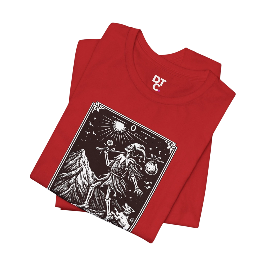 DailyThreadCo. red cotton t-shirt with 'The Fool' tarot card graphic print in black and white, featuring a skeleton figure, mountain, and sun.