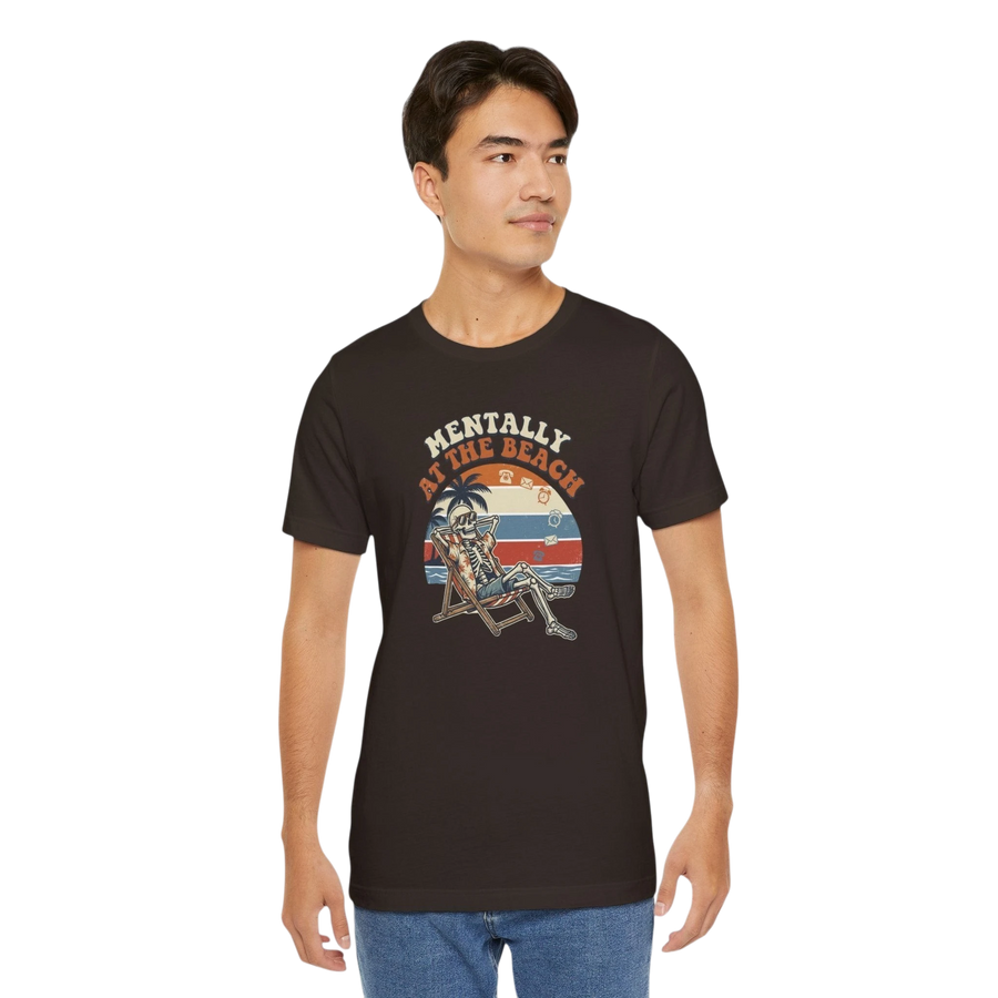 DailyThreadCo. dark brown 100% cotton t-shirt with a retro graphic of a skeleton relaxing in a beach chair under palm trees, text reads "Mentally at the Beach".
