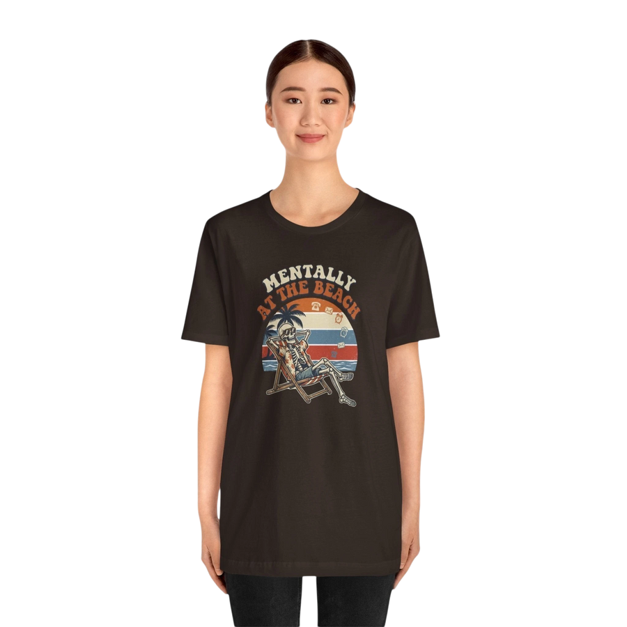 DailyThreadCo. dark brown 100% cotton t-shirt with a retro graphic of a skeleton relaxing in a beach chair under a palm tree, text reads "Mentally at the Beach".