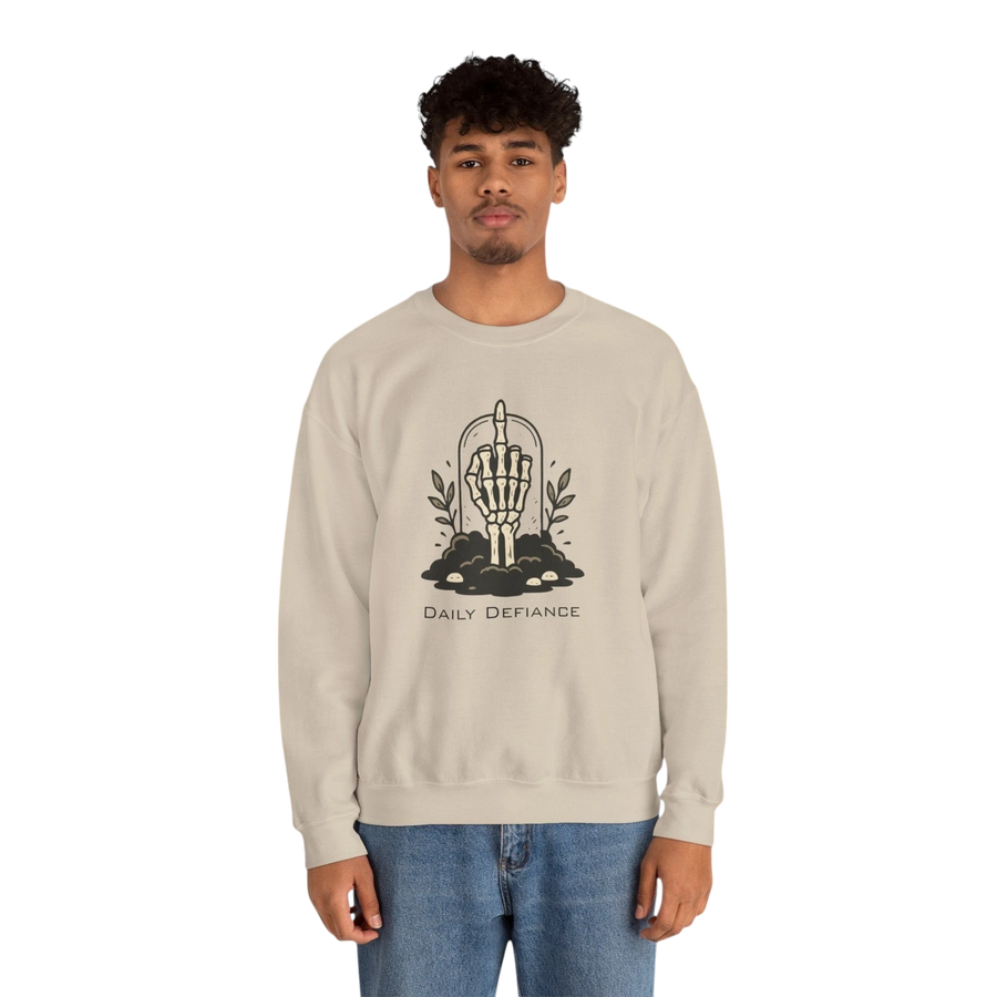 DailyThreadCo. beige crewneck sweatshirt with a black graphic of a skeleton hand giving the middle finger emerging from the ground with foliage and the words "Daily Defiance".